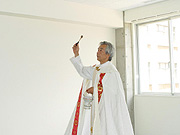 聖水を散水して新築の家を祝別する司祭